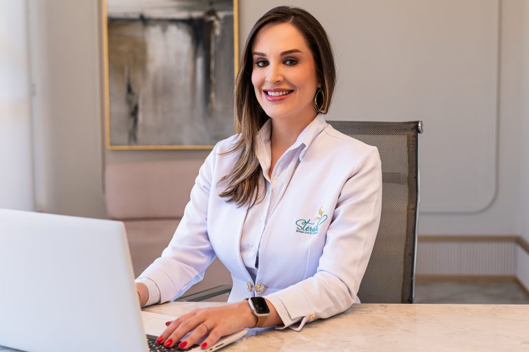 Médica atendendo em clínica com jaleco.
