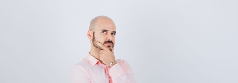 Homem de camisa rosa expressando dúvida.